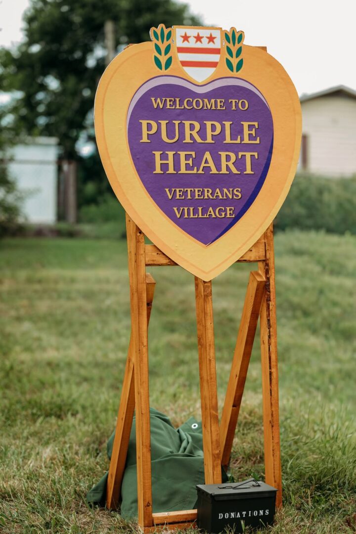 Heart-shaped sign that reads "Welcome to Purple Heart Veterans Village"
